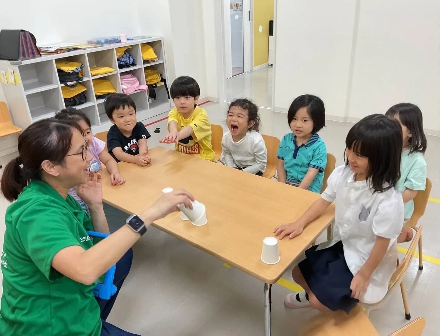 紙コップを使って講師と遊ぶ幼児クラスの子どもたち